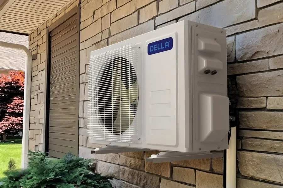 White air conditioning unit mounted on a stone wall outside a building.