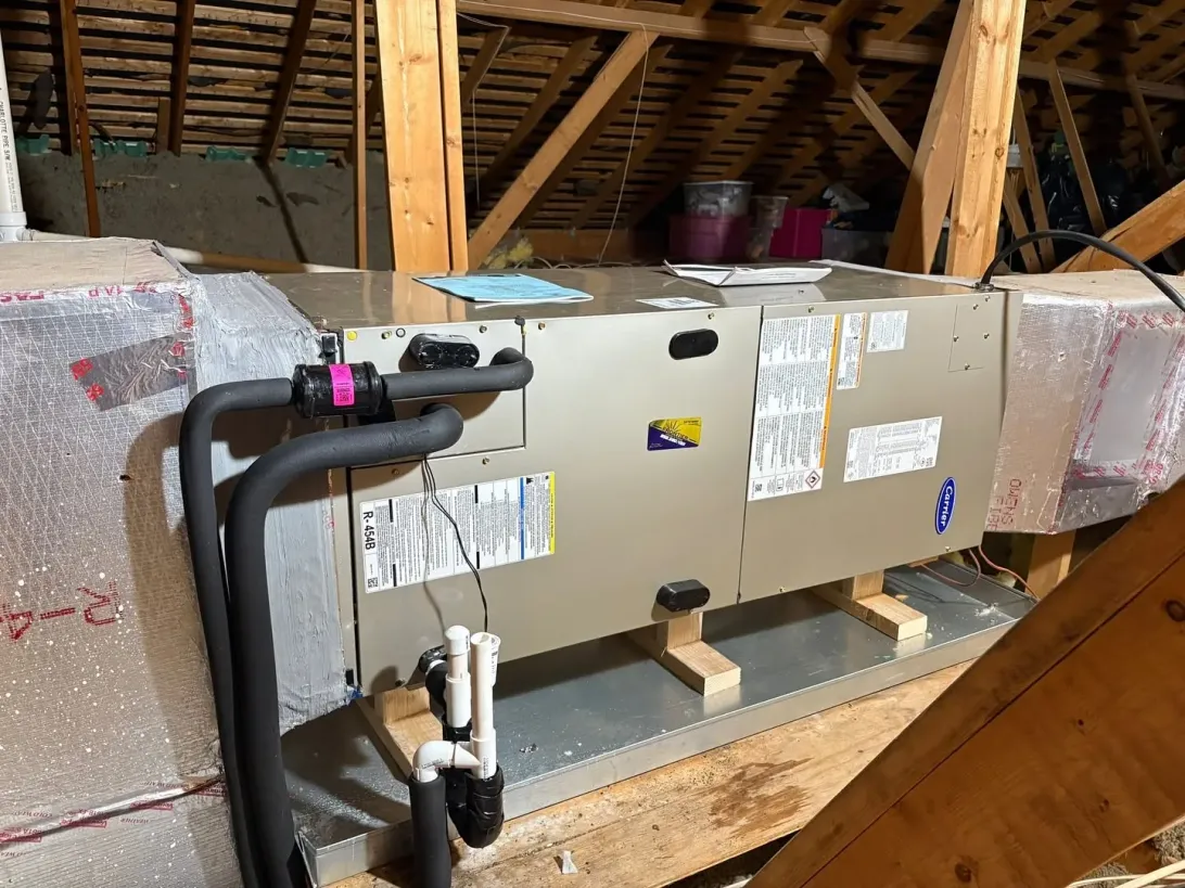 Newly installed Carrier attic air handler with insulated refrigerant lines and a PVC condensate drain