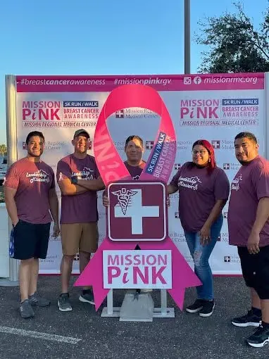 Frontier team in maroon shirts beside the Mission Pink breast cancer awareness 5K backdrop