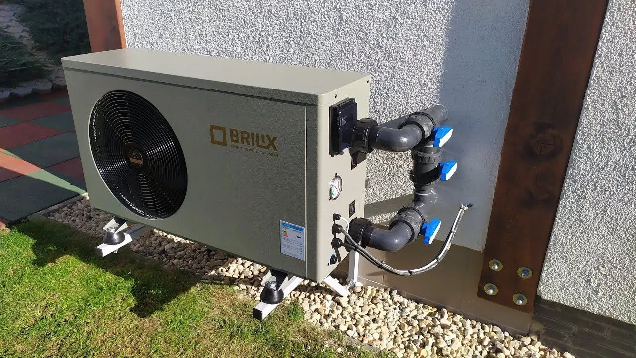 Wall-mounted outdoor HVAC unit with insulated refrigerant lines beside a fence.