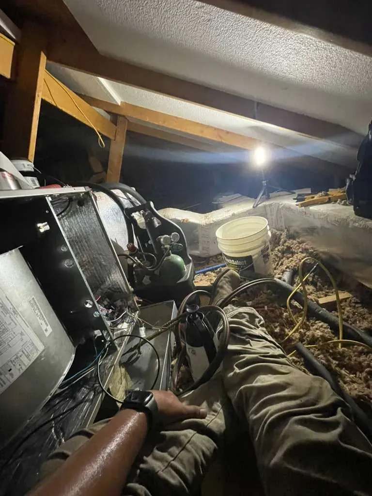 Frontier technician repairing an air handler in an attic by work light
