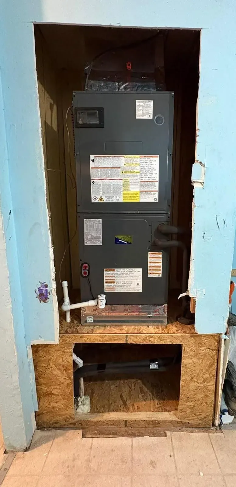 Upright air handler on a platform in an indoor equipment closet